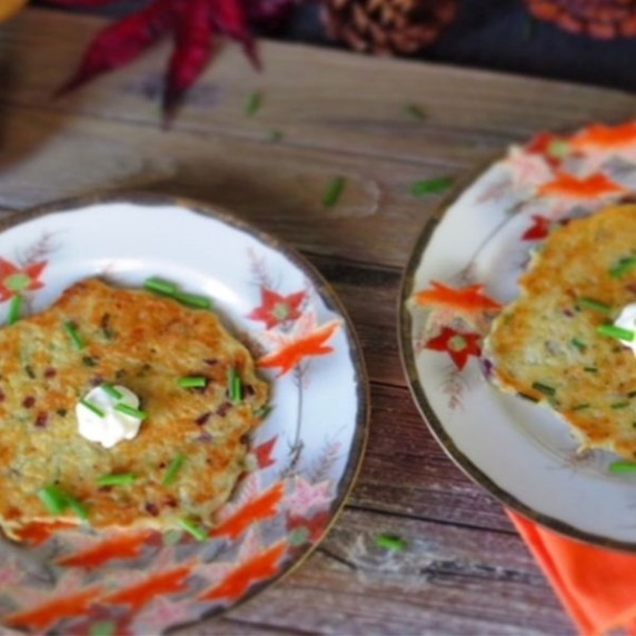 Savory potato pancake on a plate with sour cream and chives on top.