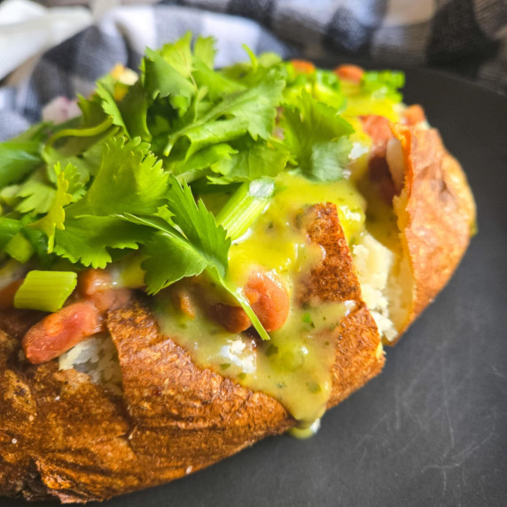 Golden brown russet stuffed with green salsa, brown beans, and a heap of fresh green cilantro.