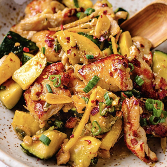 Chicken, summer squash, scallions and chili pepper flakes on a white plate