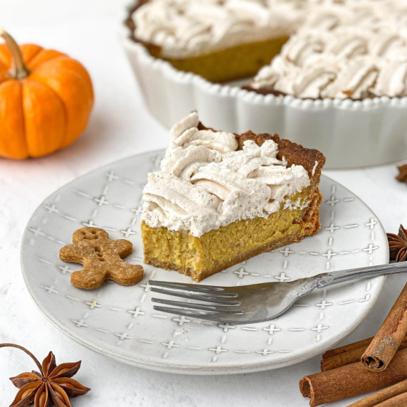 slice of gingerbread pumpkin pie on a white plate with a fork and small gingerbread man