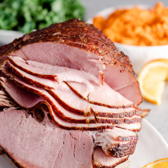 Spiral-slized ham on a platter with side dishes in the background