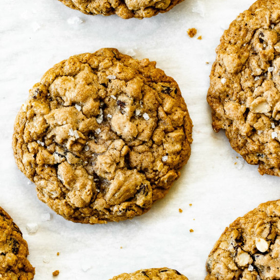 Soft and chewy gluten-free oatmeal raisin cookies sit on a white surface.