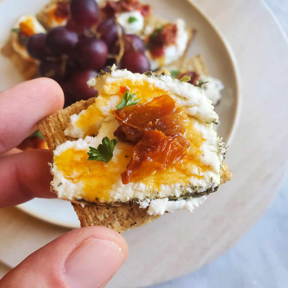 A crispy cracker topped with creamy goat's cheese, spicy red honey, and sundried tomatoes.