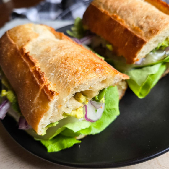 Golden baguettes, green lettuce, purple onions against a black plate