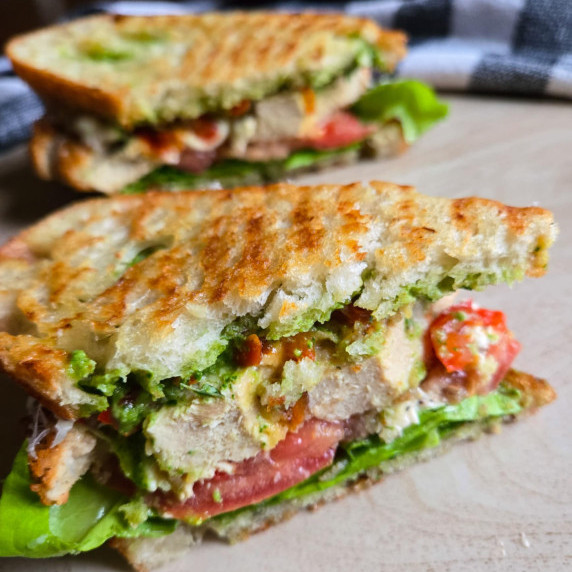 Golden brown grilled bread, red tomatoes, and pops of green from lettuce and pesto.