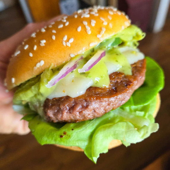 Golden bun, bright green veg & condiments, and a grilled burger