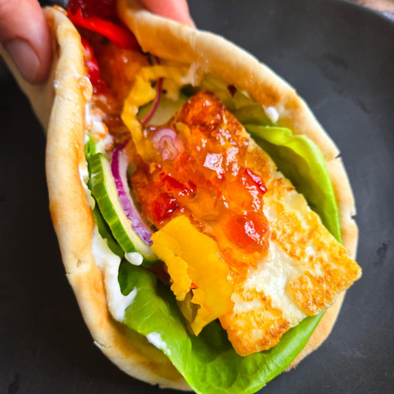 Golden halloumi, red pepper jelly, and pops of green lettuce against a black plate