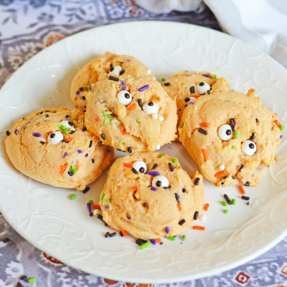 Orange Halloween cookies with sprinkles and eyeballs on a white plate