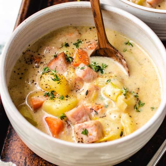 Ham and potato soup garnished with parsley in a bowl with a spoon