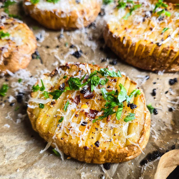 Golden brown potatoes topped with flecks of white cheese, red pepper flakes, and green parsley