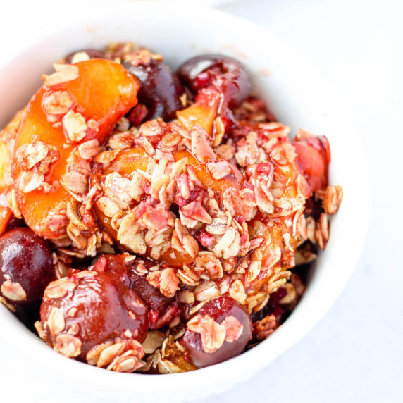 A small bowl of cherry peach crisp with oats.