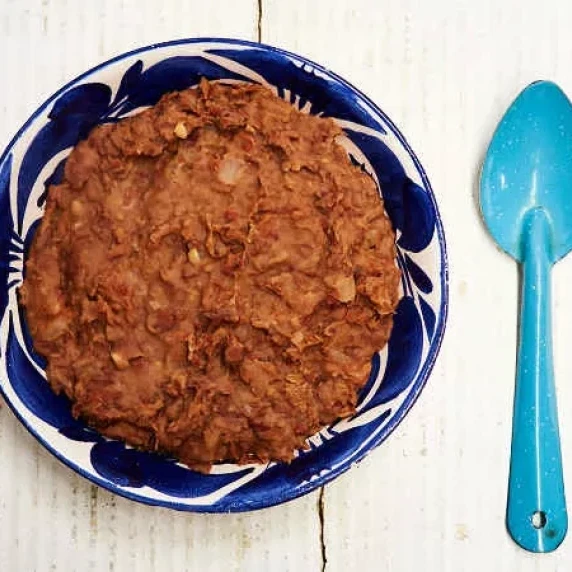 simple traditional refried beans served on a bowl with blue spoon on the side
