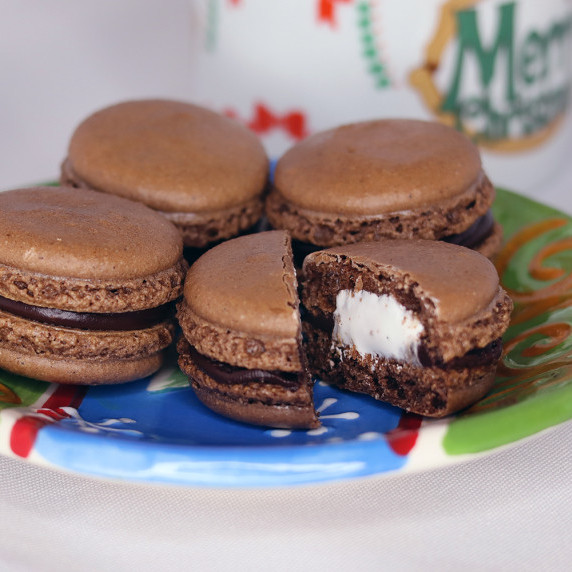 Hot cocoa macarons on a holiday plate against a white background