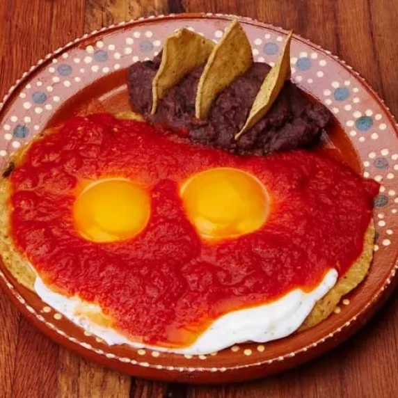Authentic Huevos Rancheros Recipe with refried beans and tortillas on the side