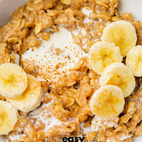 Oatmeal with banana and cream in a white bowl 