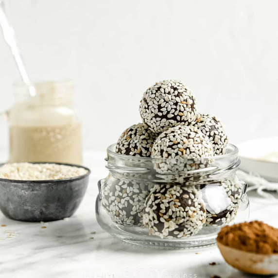 Chocolate bliss balls covered in sesame seeds in a small glas jar