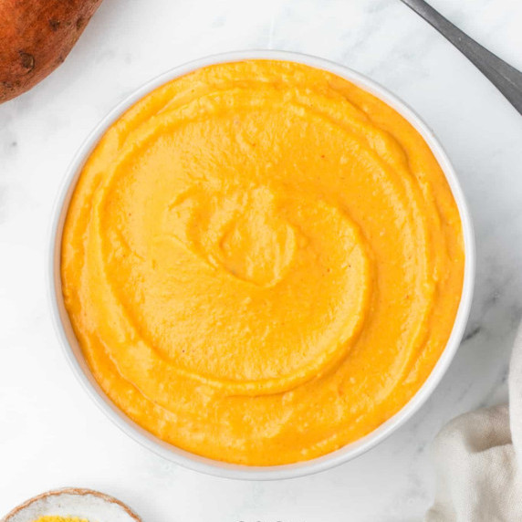 Sweet potato sauce in a white bowl on top a marble kitchen counter