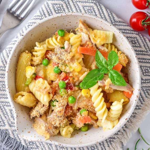 Turkey pasta with vegetable mix, breadcrumbs, & parmesan, garnished with an herb in a bowl