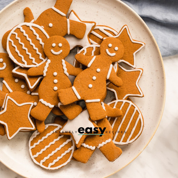 Gingerbread cookies in different shapes decorated with white icing on a white plate