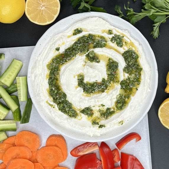 Whipped feta dip topped with a green onion and parsley sauce served with fresh vegetables.