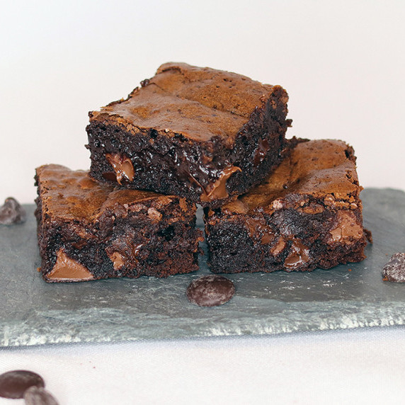 Three brownies on a slate platter against a white background