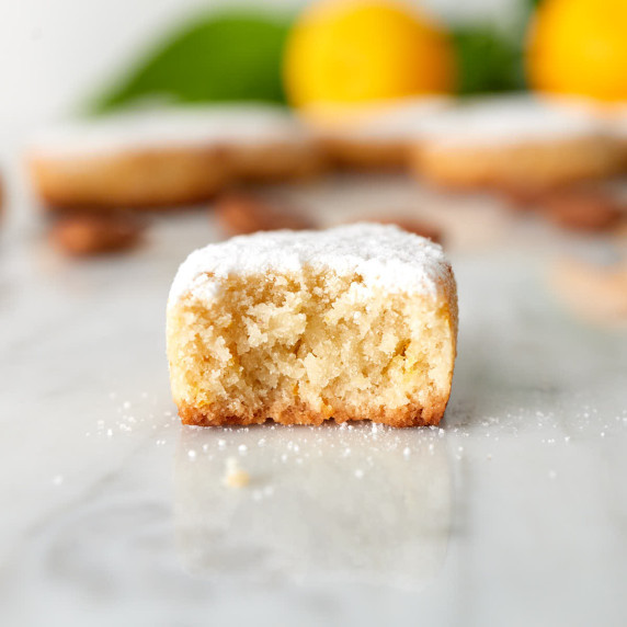 Half Italian ricciarelli cookie on marble table.