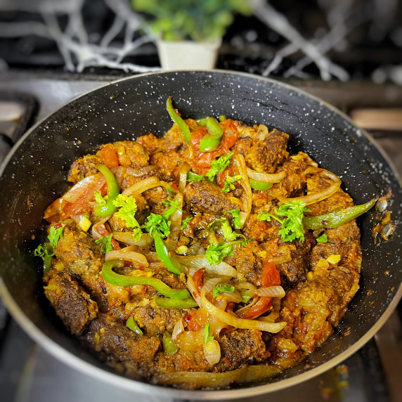 Seekh kabab karahi arranged in a pan placed on stovetop 