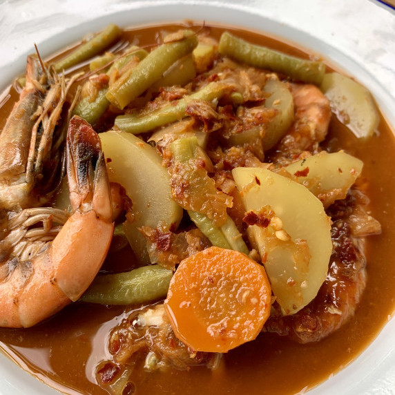Kaeng som, Southern Thai curry with shrimp and vegetables, in a white dish.
