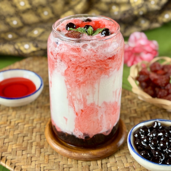 A glass of strawberry boba with tapioca pearls and strawberry syrup.