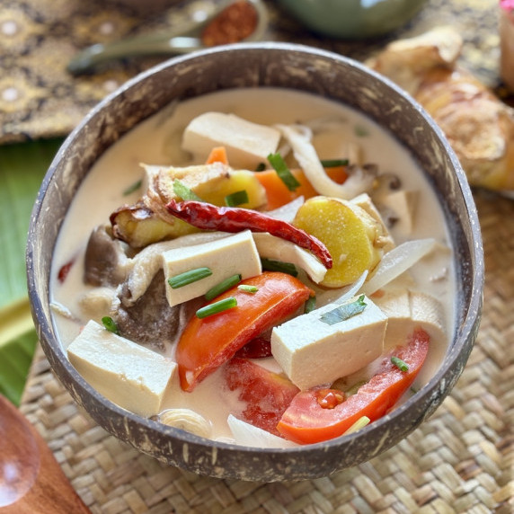 Thai tofu soup with coconut milk, a vegetarian tom kha, served in a coconut shell.