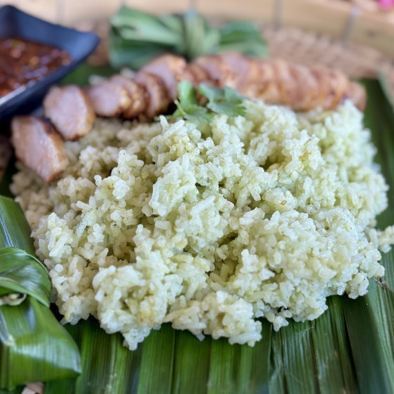 Thai pandan rice served with grilled pork and a dipping sauce.