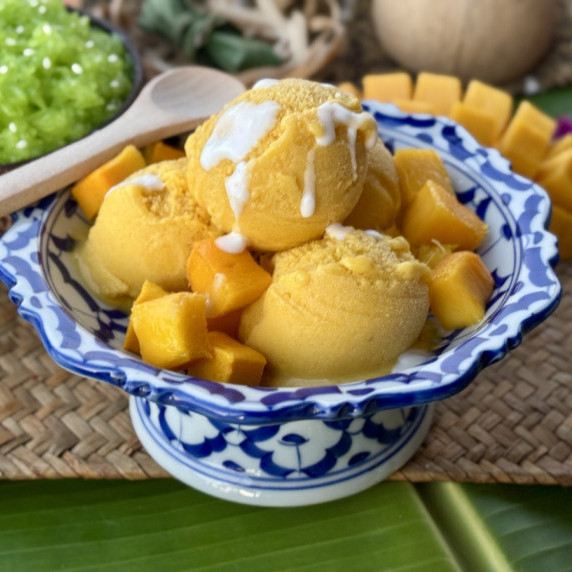 Mango ice cream in a dessert bowl, topped with condensed milk.