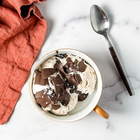 chai spiced ice cream with salted chocolate in a bowl with a spoon and towel on a counter top