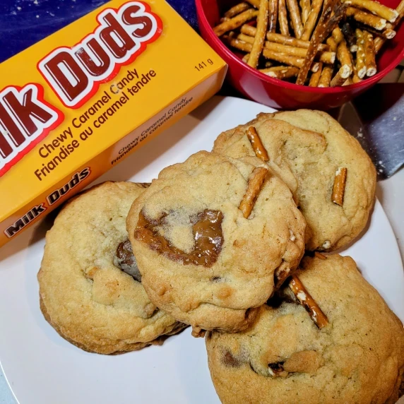 cookies with a bowl of pretzels and a box of milk duds.