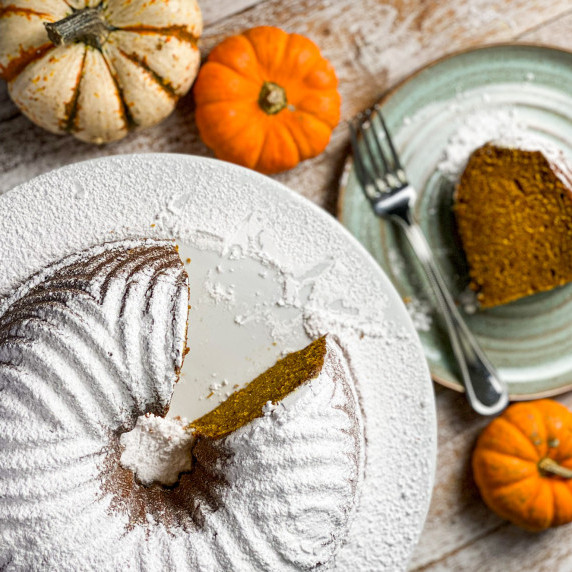 Powdered sugar covered pumpkin bundt cake with mini pumpkins.