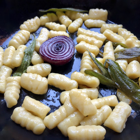 A skillet full of fluffy, tender-soft homemade potato gnocchi with a crispy sage & EVOO sauce!