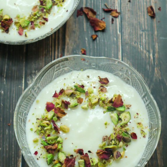 A bowl of middle eastern pudding with chopped pistachios on top 