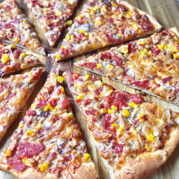 Easy Homemade Sliced Sweetcorn, Tuna Pizza on a wooden round board