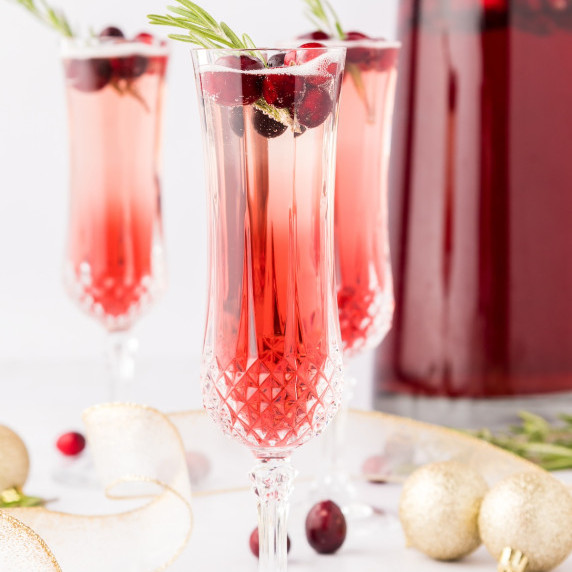 cranberry mimosas in champagne flutes with cranberries and rosemary 