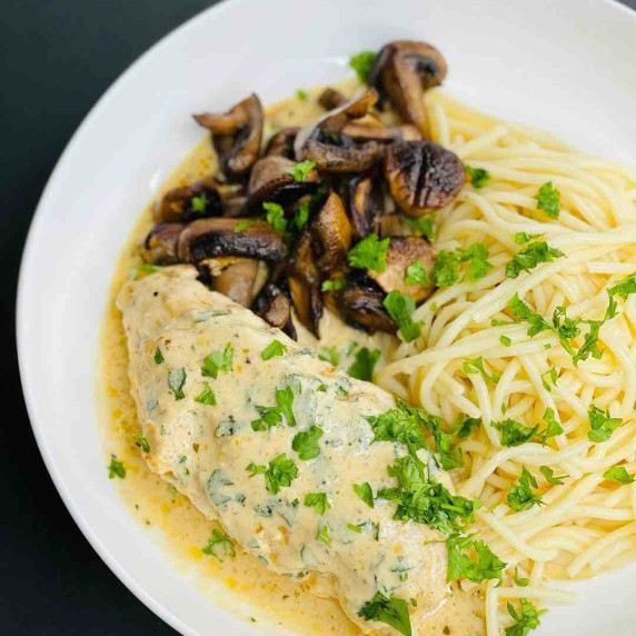 Creamy Boursin Cheese Chicken In a white bowl served with sautéed mushroom and spaghetti, garnished 