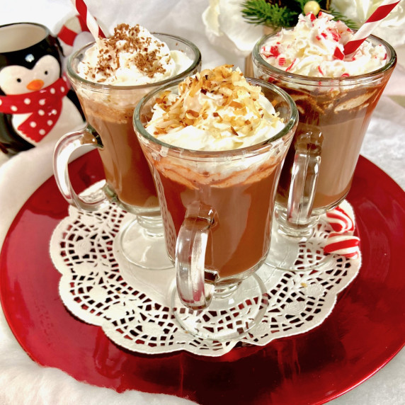 Three glass mugs of hot chocolate on red serving platter.