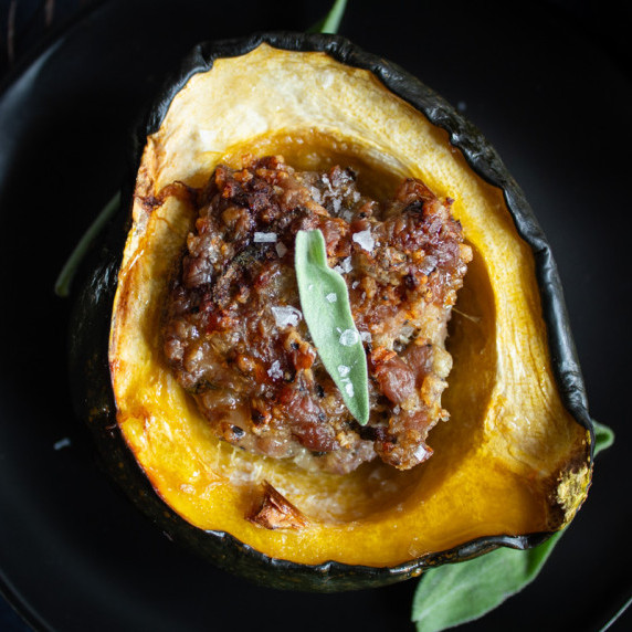 Sausage stuffed acorn squash with sage leaf garnish