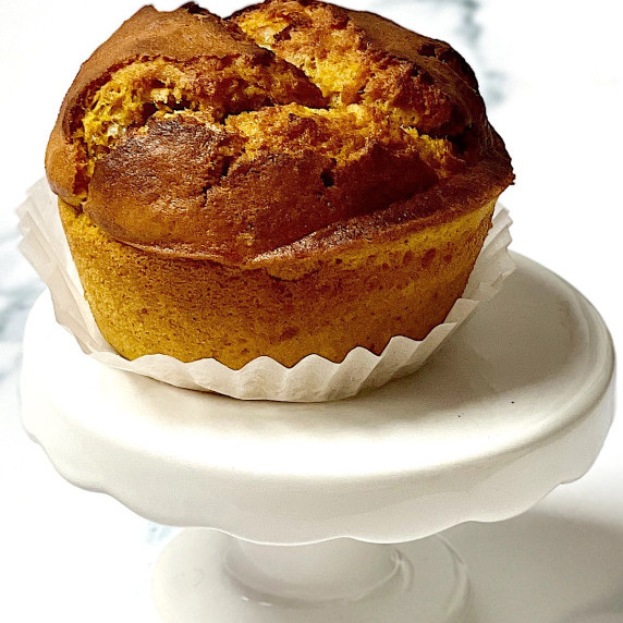 a jumbo pumpkin muffin on a white cupcake stand