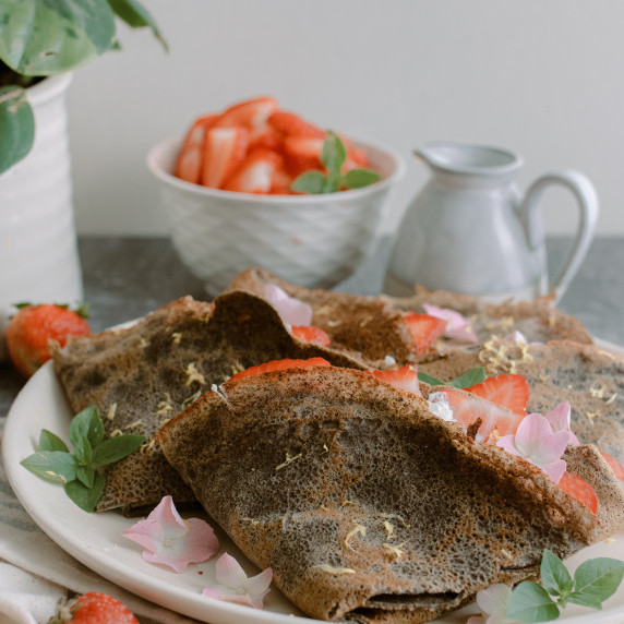 buckwheat crepes arranged on a white plate with strawberries 