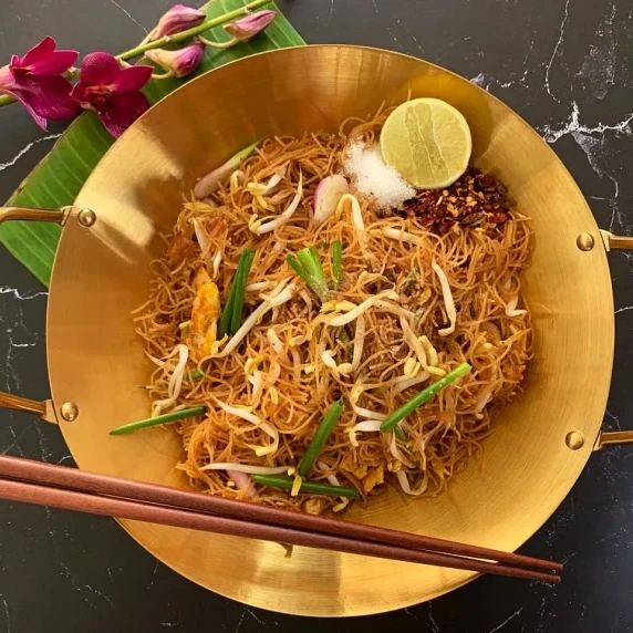 Rice vermicelli stir-fry in a bowl with chopsticks and lime