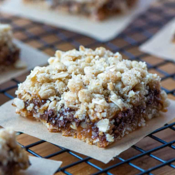 Carmelitas cookie bar on a piece of parchment paper on a cooling rack in front of other carmelitas 