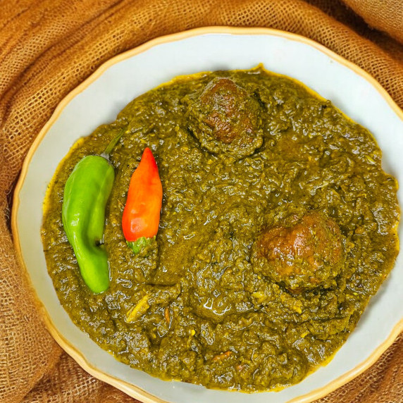 Kofta palak arranged in white bowl on a jute mat