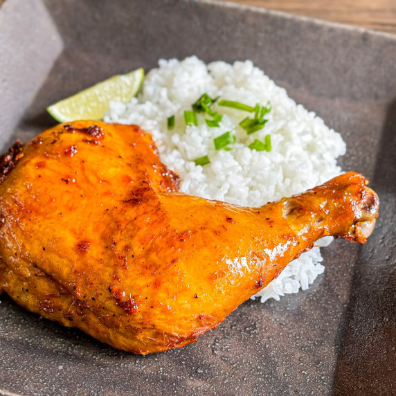 Close-up of inasal chicken served with jasmine rice in a dark dish.