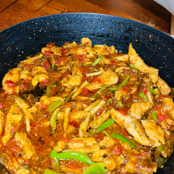 Ginger chicken arranged in black bowl on jute mat 