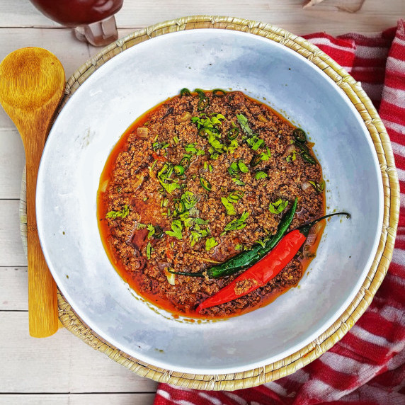 Keema curry arrange in white bowl placed on bamboo mat